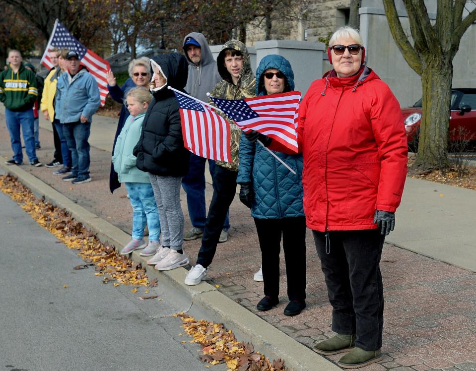 Parade goers wave flags along Capitol Avenue as they watch the Springfield Veterans Day Parade go by Friday Nov. 11, 2022.