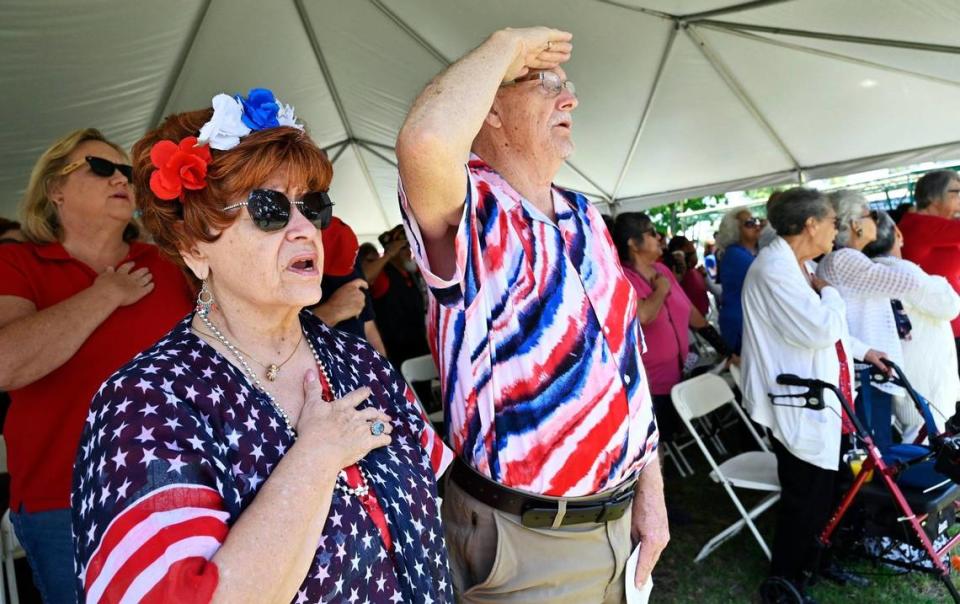 Felicia Kellenberger, left, with Bob Mitchell to the right, join over a hundered others beneath a canopy singing the Star Spangled Banner at the 60th VFW Memorial Day Service held at Fresno Memorial Gardens Monday, May 29, 2023 in Fresno.