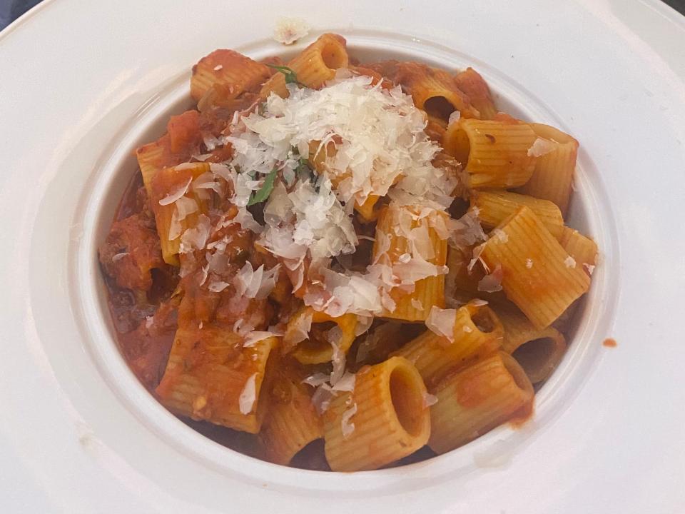 plate of pasta with red sauce and cheese in a white serving bowl