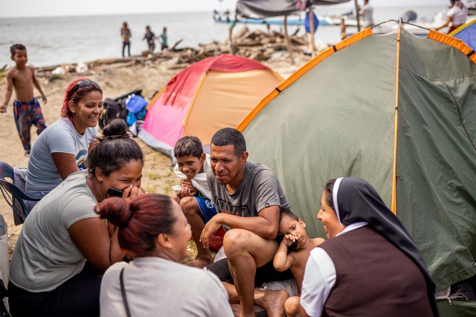 Yudis Paola Diaz Macia, bottom left, and Sister Digna Gloria Gelpud Mallama, right, talk to Venezuelan migrants Genesis Madelaine Gonzalez Perez, left, Yorman Jesus Mendoza Miers, center, and their children in a camp in Necoclí. | Spenser Heaps, Deseret News