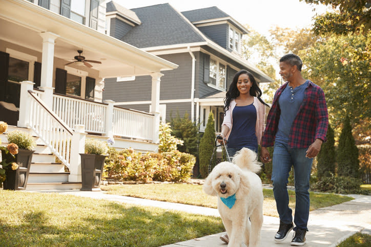 A couple walking their dog through a neighborhood.