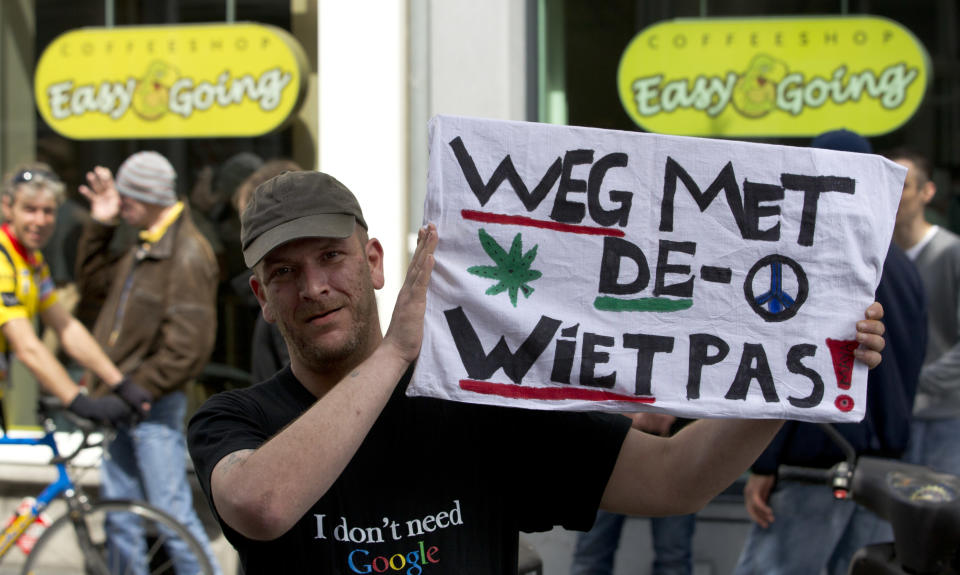 A demonstrator holds a sign reading "get rid of the weed pass" outside coffeeshop Easy Going in Maastricht, southern Netherlands, Tuesday May 1, 2012. A policy barring foreign tourists from buying marijuana in the Netherlands goes into effect in parts of the country Tuesday, with a protest planned in the southern city of Maastricht. Weed is technically illegal in the Netherlands, but it is sold openly in small amounts in designated cafes under the country's famed tolerance policy. The government has said that as of May 1, only holders of a "weed pass" will be allowed to purchase the drug, and nonresidents aren't eligible. (AP Photo/Peter Dejong)