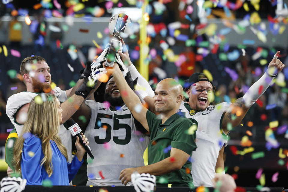 Baylor offensive lineman Connor Galvin, left, offensive lineman Xavier Newman-Johnson (55), head coach Dave Aranda, right, and linebacker Terrel Bernard, right, hold up the trophy as ABC commentator Molly McGrath, left, looks on after an NCAA college football game against Oklahoma State for the Big 12 Conference championship against Oklahoma State in Arlington, Texas, Saturday, Dec. 4, 2021. (AP Photo/Tim Heitman)