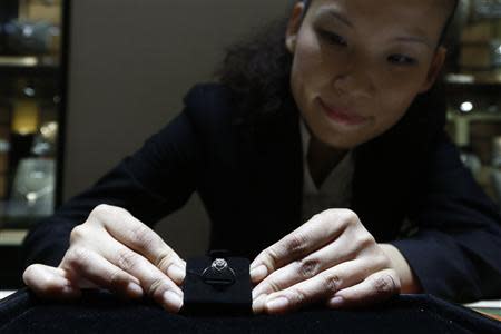 A sales assistant displays a diamond ring at a Tiffany store in Shanghai, September 16, 2013. REUTERS/Aly Song