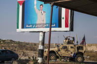 U.S. military convoy drives the he town of Qamishli, north Syria, by a poster showing Syrain President Bashar Aassad Saturday, Oct. 26. 2019. A U.S. convoy of over a dozen vehicles was spotted driving south of the northeastern city of Qamishli, likely heading to the oil-rich Deir el-Zour area where there are oil fields, or possibly to another base nearby. The Syrian Observatory for Human Rights, a war monitor, also reported the convoy, saying it arrived earlier from Iraq. (AP Photo/Baderkhan Ahmad)