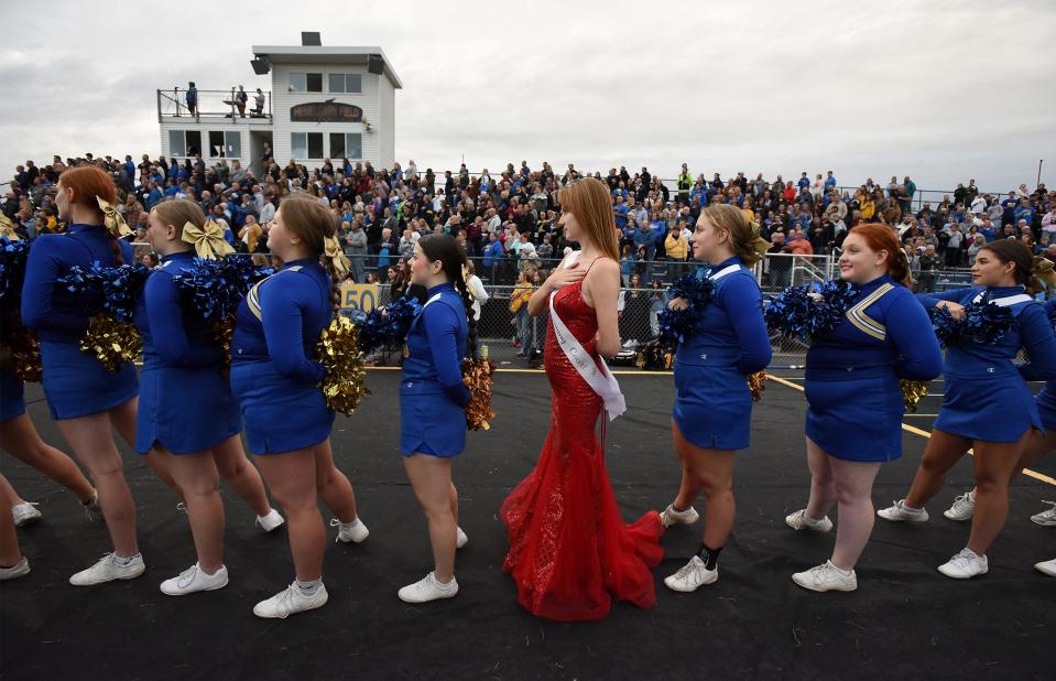 Ida High School junior cheerleader Kilee Busby wearing her red evening gown as a member of this years homecoming court stands with the cheerleading squad during the National Anthem homecoming game October 6, 2023.