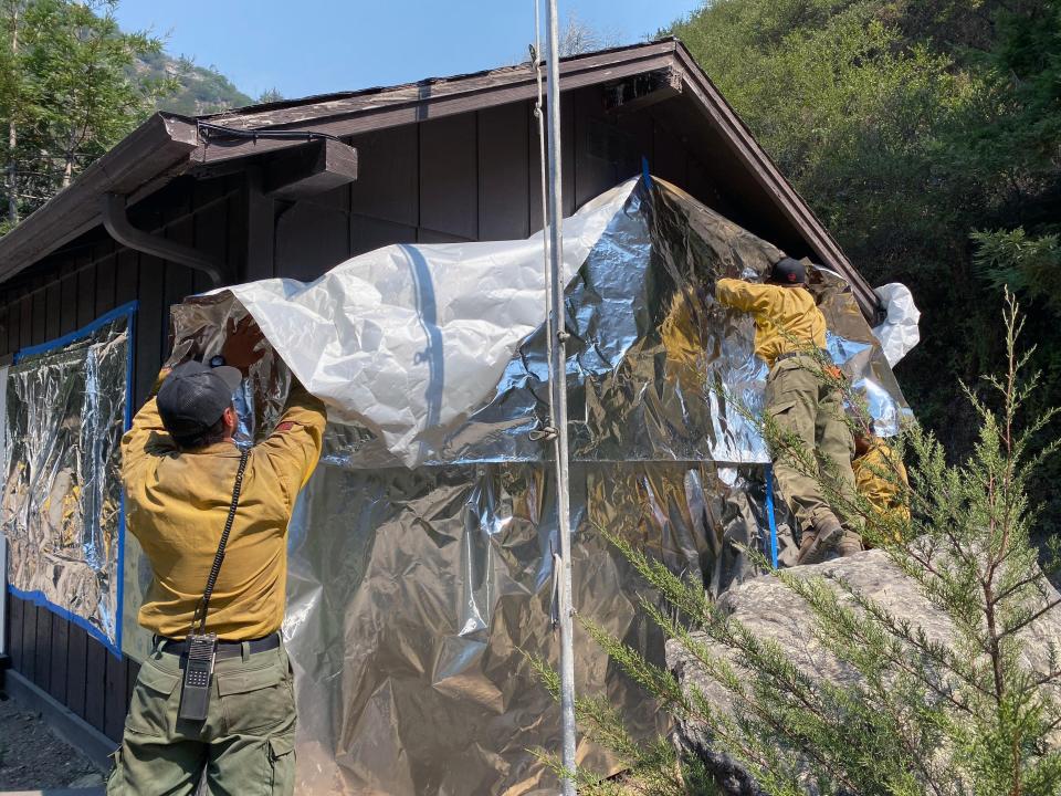 Firefighters wrap a structure at Limekiln State Park in foil to protect it from the Dolan Fire. Sept. 6, 2020.