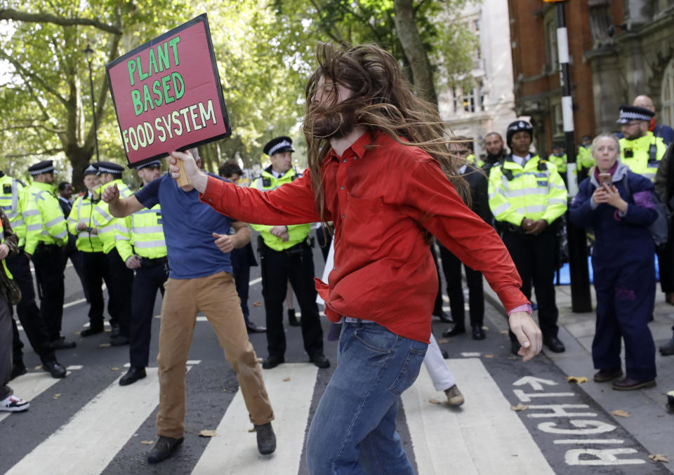 Climate demonstrators dance in front of police officers near Parliament in London, Tuesday, Oct. 8, 2019. Police are reporting they have arrested more than 300 people at the start of two weeks of protests as the Extinction Rebellion group attempts to draw attention to global warming. (AP Photo/Kirsty Wigglesworth)