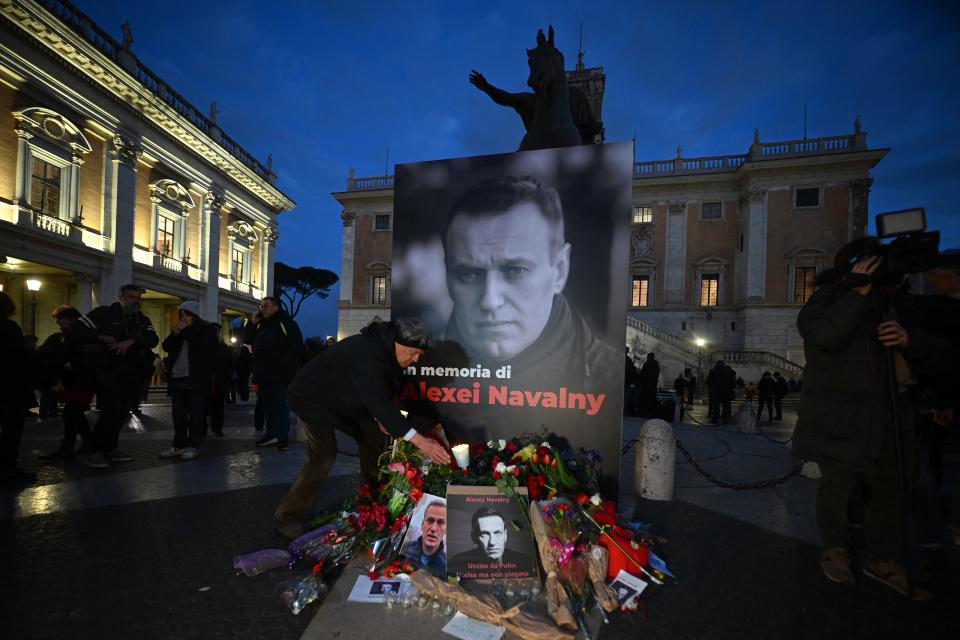 TOPSHOT - People bring flowers and candles for a vigil in honor of Kremlin's critic Alexei Navalny following is death, on February 19, 2024 in front of Rome's city hall. Russia reported Navalny's death in an arctic prison on February 16, 2024 and his mother has been denied access to the body, enraging supporters who have accused authorities of trying to cover up Navalny's "murder". (Photo by Filippo MONTEFORTE / AFP)