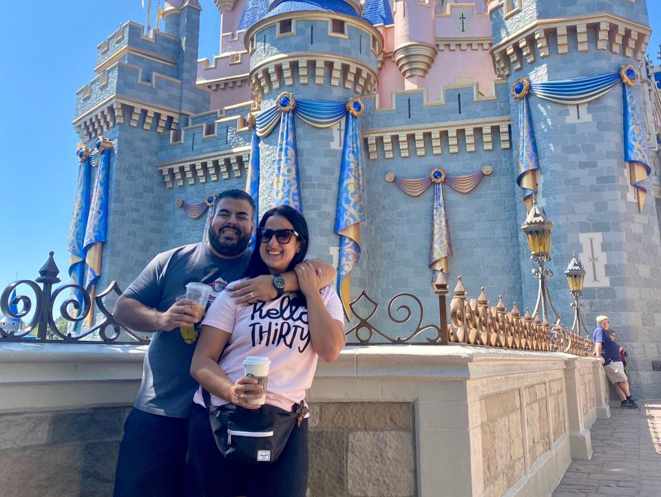 stephanie and her husband posing in front of cinderella castle at disney world