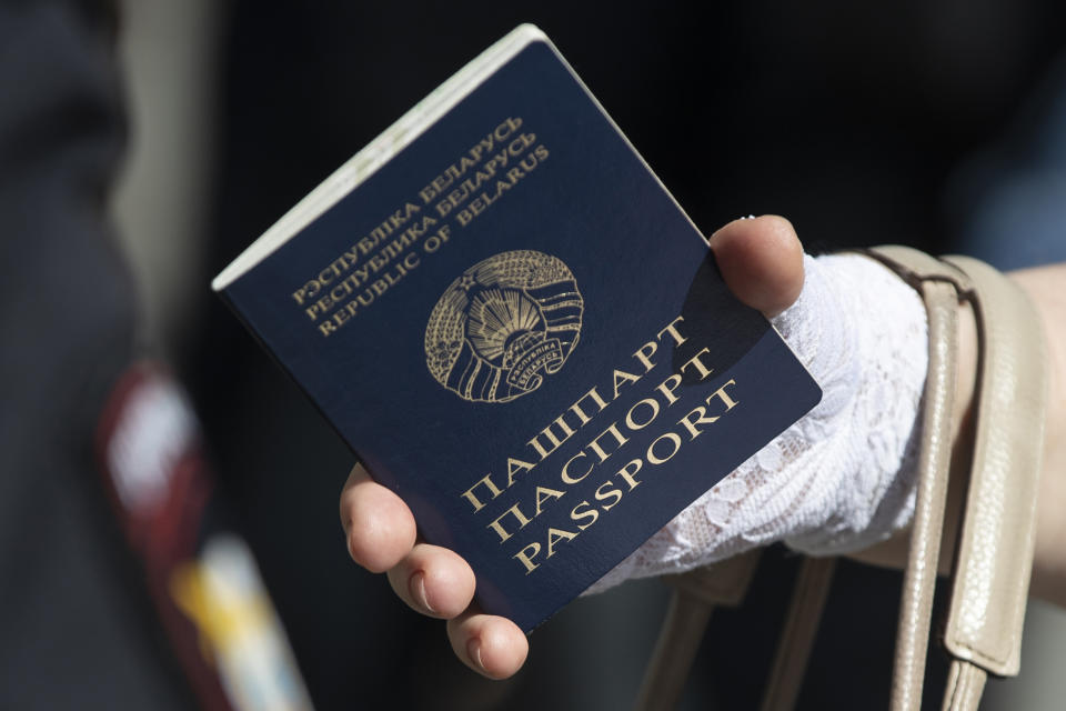 FILE - A woman holds a Belarusian passport as she waits to vote in the Belarusian presidential election outside the Belarusian Embassy in Moscow, Russia, on Sunday, Aug. 9, 2020. Belarus has stopped renewing passports at its embassies abroad, and hundreds of thousands of Belarusians who have fled President Alexander Lukashenko's repressive regime cannot update their travel documents without returning home and risking possible arrest. (AP Photo/Pavel Golovkin, File)