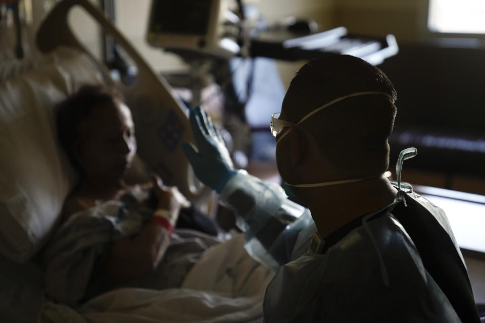 Chaplain Elias Mena prays with COVID-19 patient Zoraida Escorba at Providence Holy Cross Medical Center in the Mission Hills section of Los Angeles on Friday, Jan. 15, 2021. (AP Photo/Jae C. Hong)