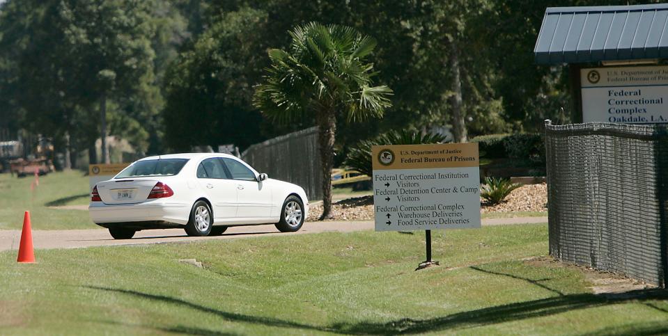 In this Sept. 26, 2006, file photo a person drive through the gates of a federal prison in Oakdale, La. The federal Bureau of Prisons is locking all its 146,000 inmates in their cells for the next two weeks in an unparalleled effort to slow the spread of the coronavirus, as the focus shifts to the Louisiana compound, where five inmates have died.