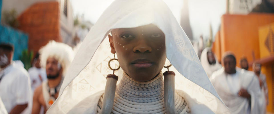 A closeup of Shuri looking solemn as she walks in a procession