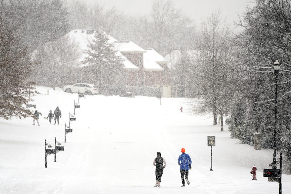 Joggers run down a street empty of cars Thursday, Feb. 18, 2021, in Nolensville, Tenn. A second winter storm in a week is bringing more snow to much of Tennessee. (AP Photo/Mark Humphrey)