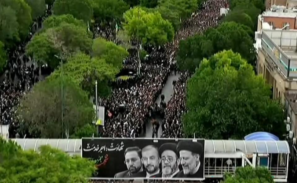 This grab taken from handout video footage released by Iran Press on May 21, 2024 shows people gathering to mourn the Iranian President and seven members of his entourage during a funerary procession (IRAN PRESS/AFP via Getty Images)