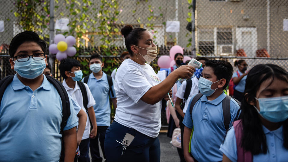 A teacher takes the temperature of students arriving for the first classes at a public school in the Bronx borough in New York, on Monday.