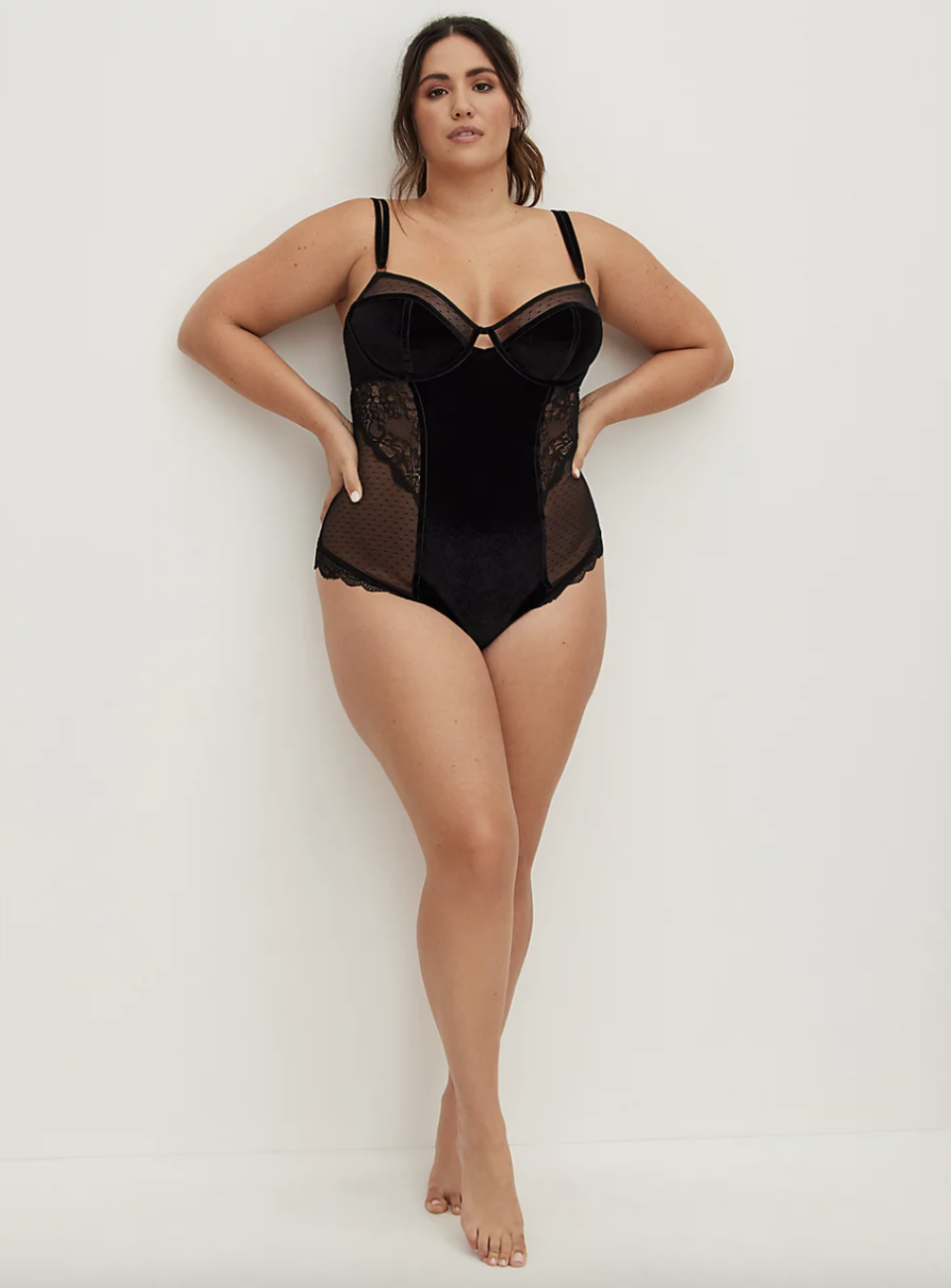 brunette plus size model in black Torrid Velvet & Lace Bodysuit (Photo via Torrid)