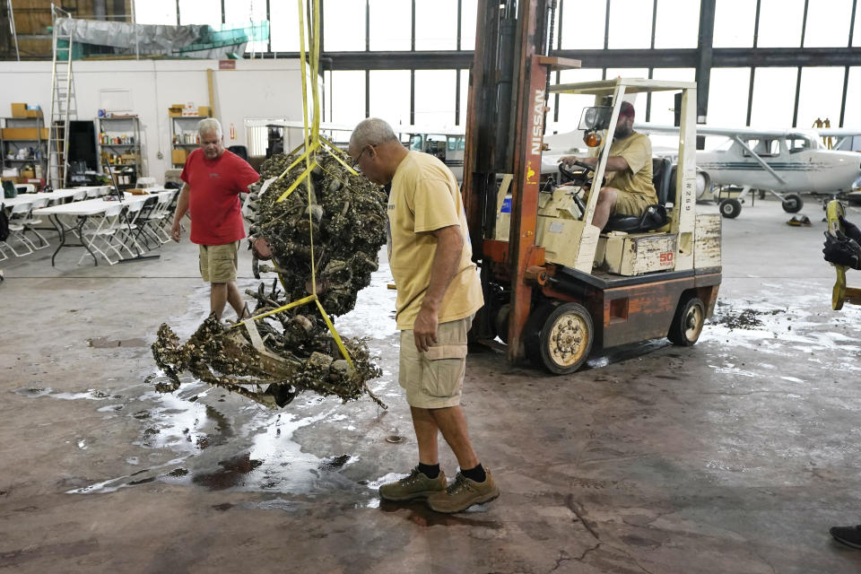 The 1,200-pound mussel-encrusted engine from a P-39 World War II-era fighter plane flown by a member of the famed Tuskegee airmen is moved, Thursday, Aug. 17, 2023 at the Tuskegee Airmen National Historical Museum in Detroit. The plane was flown by a member of the famed Tuskegee airmen that crashed during training nearly 80 years ago near Port Huron, about 60 miles northeast of Detroit. (AP Photo/Carlos Osorio)