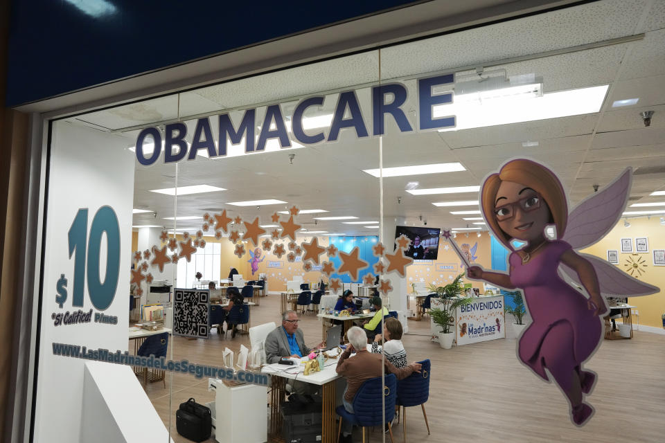 An insurance agent talks with clients inside the main location of Las Madrinas de los Seguros, Spanish for "The Godmothers of Insurance," at a shopping center in Miami, Tuesday, Dec. 5, 2023. (AP Photo/Rebecca Blackwell)