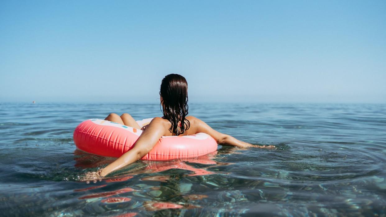 young woman in a sprinkled doughnut float at the beach