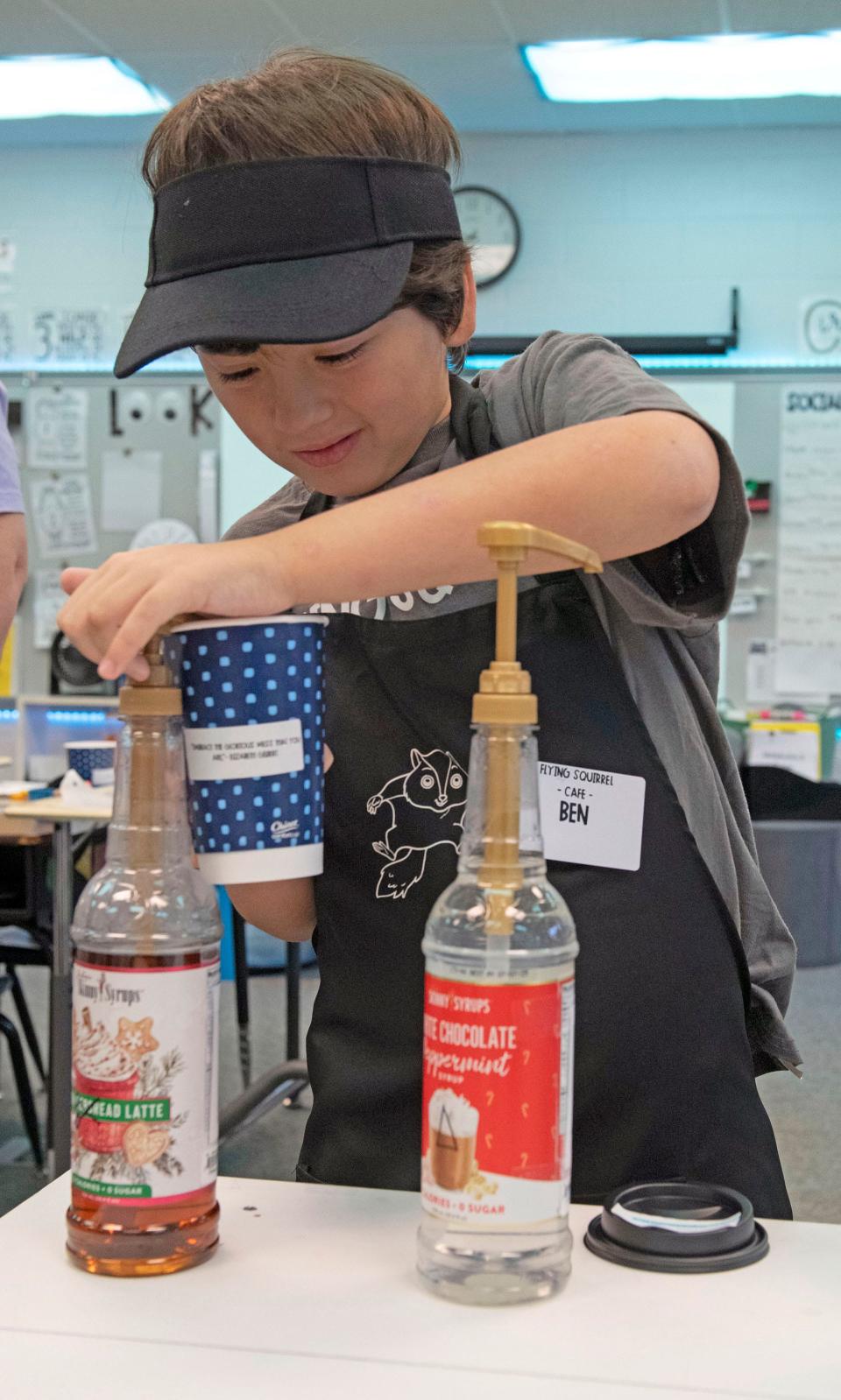 Rhodes Elementary School student and Flying Squirrel Café employee Ben Burnett works to fulfill a specialty drink order on Friday, Dec. 1, 2023. The student-run business helps the children learn life and social skills.