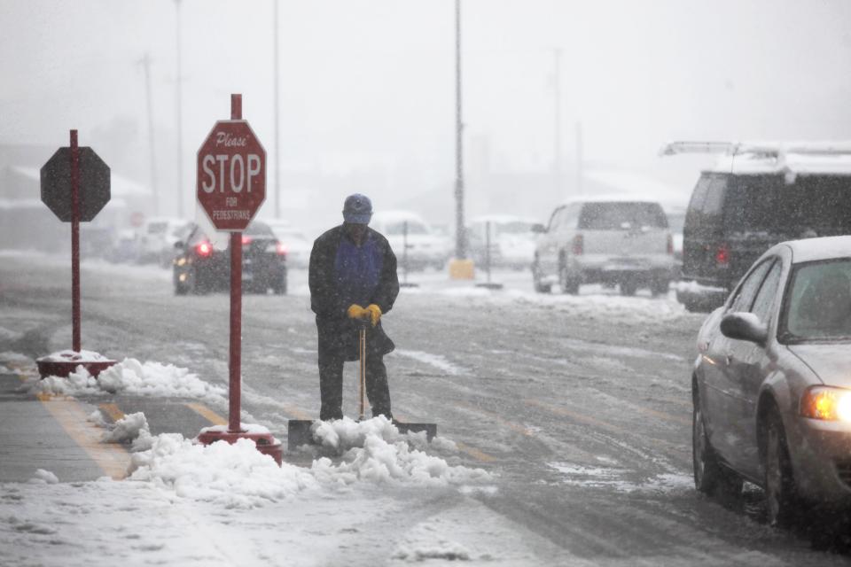 Neal Abernathy clears snow at the entrance of the store during a snow storm in Rapid City