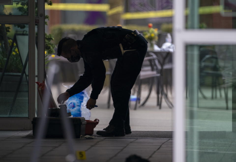 A member of the RCMP is silhouetted as he investigates the scene at the Lynn Valley Library, in North Vancouver, British Columbia Saturday, March 27, 2021. Police say multiple victims were stabbed inside and outside the library today. (Jonathan Hayward/The Canadian Press via AP)