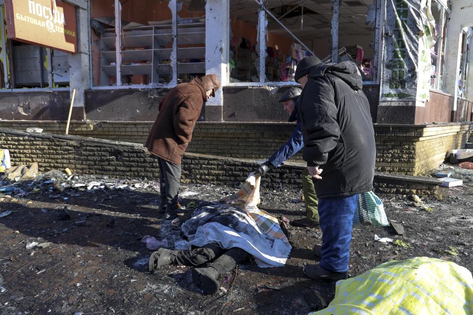 People try to recognise a body of a victim killed during the shelling that Russian officials in Donetsk said was conducted by Ukrainian forces, in Donetsk, Russian-controlled Donetsk region, eastern Ukraine in Donetsk, Ukraine, Sunday, Jan. 21, 2024. Local officials say at least 18 people have been killed by shelling of a market in Russian-occupied Ukraine. The attack hit Tekstilshchik, a suburb of the city of Donetsk, on Sunday. Alexei Kulemzin, the city's Russian-installed mayor, said that the shells had been fired by the Ukrainian military. (AP Photo/Alexei Alexandrov)