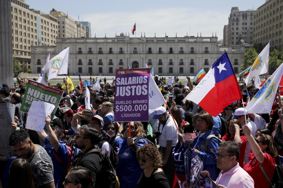 Anti-government demonstrators march past La Moneda presidential palace in Santiago, Chile, Wednesday, Oct. 30, 2019. President Sebastian Pinera cancelled two major international summits after nearly two weeks of nationwide protests over economic inequality that have left at least 20 dead and damaged businesses and infrastructure around the country. (AP Photo/Rodrigo Abd)