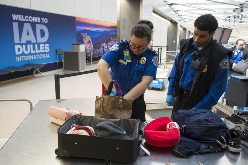 Transportation Security Administration (TSA) Officers search handbags which were packed in a suitcase at a checkpoint at Dulles International Airport in Dulles, Va., Tuesday, March 26, 2019. (AP Photo/Cliff Owen)