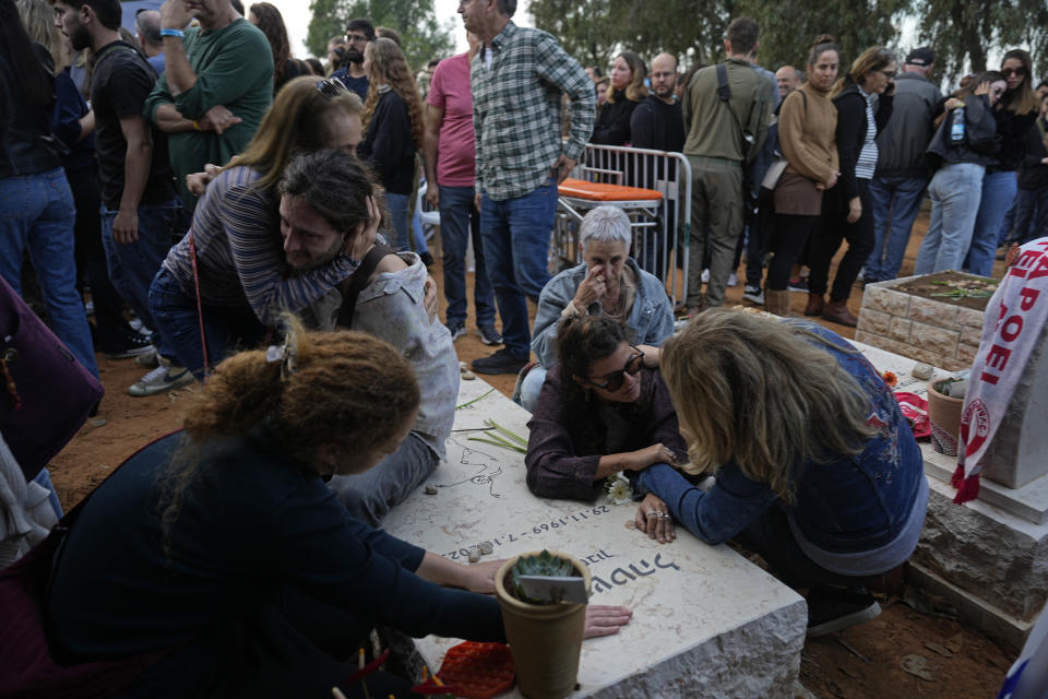 Friends that attended the funeral of 26-year-old Alon Shamriz mourn over the grave of a victim of the Oct. 7th attack buried in the same cemetery in Kibbutz Shefayim, Israel, Sunday Dec. 17, 2023. Shamriz was one of three hostages mistakenly shot to death by Israeli troops Friday in a neighborhood of Gaza City.(AP Photo/Ohad Zwigenberg)