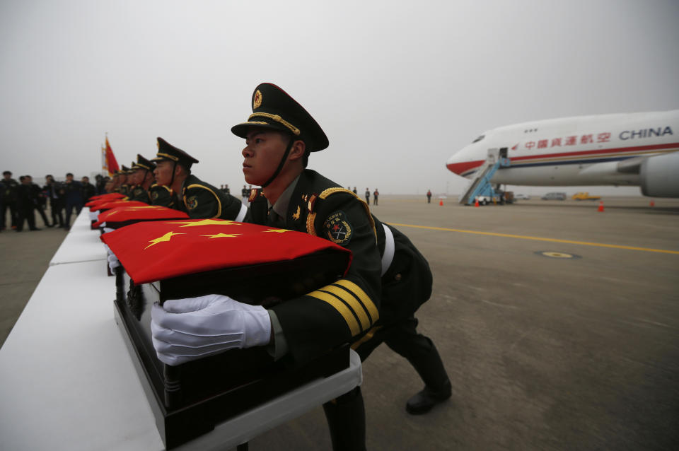 Chinese honor guards lift caskets containing the remains of Chinese soldiers after caskets were covered with Chinese national flags during the handing over ceremony of the remains at the Incheon International Airport in Incheon, South Korea Friday, March 28, 2014. The remains of more than 400 Chinese soldiers killed during the 1950-53 Korean War were transferred from the temporary columbarium in South Korea to the airport to return home for permanent burial. (AP Photo/Kim Hong-ji, Pool)