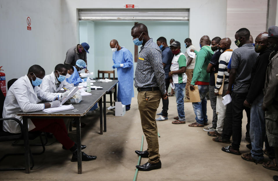 In this photo taken Monday, June 1, 2020, truck drivers entering Kenya queue to be tested for the coronavirus on the Kenya side of the Namanga border crossing with Tanzania. Africa's long-haul truckers carry food, fuel and other essential supplies along dangerous roads, but now they say they are increasingly accused of carrying the coronavirus as well. The drivers say they are stigmatized and even threatened in some countries. (AP Photo/Brian Inganga)