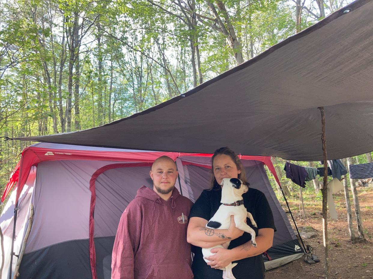 Lauren Bahre and her husband, Benji, stand under the awning the tent they've been forced to live in because of their lack of finances. Lauren is holding the couple's dog, Ellie.