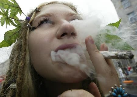 A woman with marijuana plant leaves in her hair smokes during a protest march in Berlin to legalize the sell of hashish and marijuana in Germany August 23, 2003. REUTERS/Fabrizio Bensch
