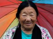 A Tibetan woman smiles under an umbrella during a downpour in the northern Indian hill town of Dharamsala August 6, 2011. REUTERS/Adnan Abidi