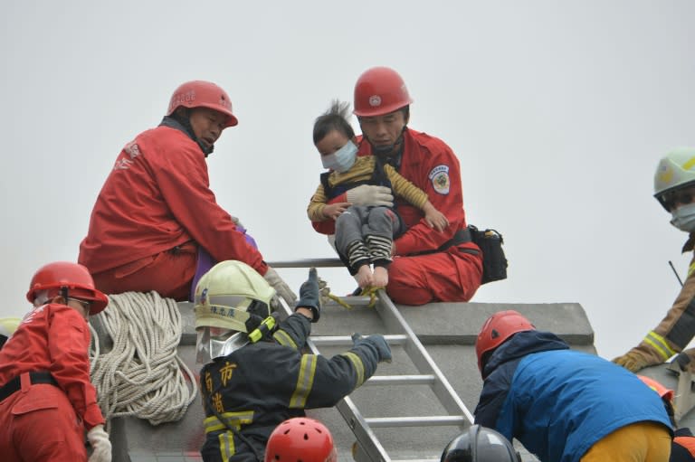 Rescue personnel help a young victim at the site of a collapsed building in the southern Taiwanese city of Tainan following a strong 6.4-magnitude earthquake that struck the island early on February 6, 2016