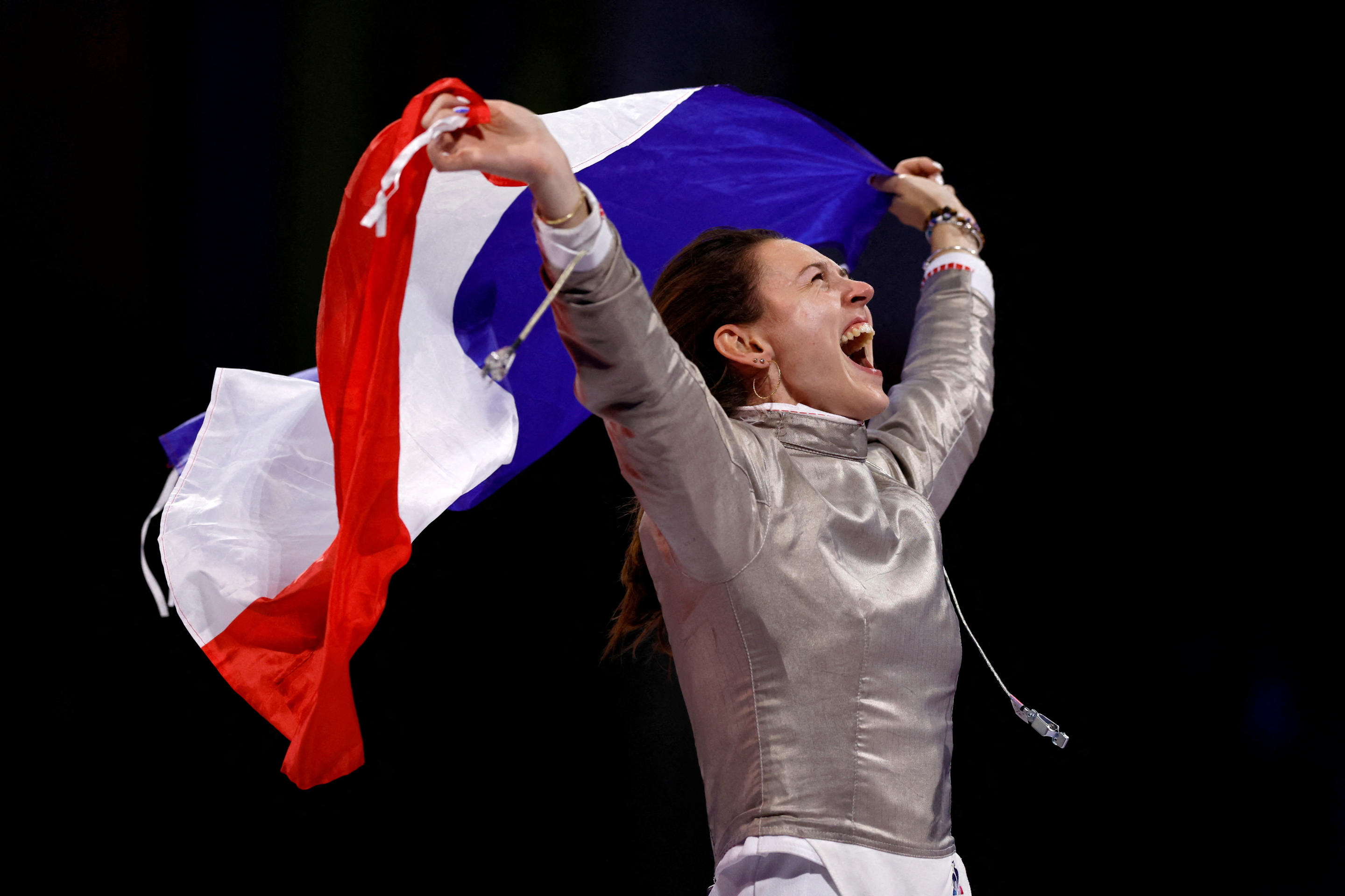 Manon Apithy-Brunet of France celebrates with flag after winning her gold medal bout against Sara Balzer of France in the Women's Sabre Individual Gold Mdl Bout on July 29, 2024. (Albert Gea/Reuters)