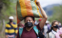 Honduran migrants hoping to reach the U.S. border carry their belongings as they walk along a highway in Chiquimula, Guatemala, Saturday, Jan. 16, 2021. Guatemalan authorities estimated that as many as 9,000 Honduran migrants crossed into Guatemala as part of an effort to form a new caravan to reach the U.S. border. (AP Photo/Sandra Sebastian)