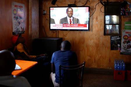 Men watch a television set as opposition leader Raila Odinga addresses the nation during a press conference, at the Mathare slum, in Nairobi, Kenya August 16, 2017. REUTERS/Siegfried Modola