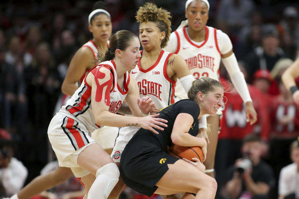 Ohio State guard Taylor Mikesell, left, fouls Iowa guard Kate Martin, right, as Ohio State guard Rikki Harris, back center, is caught in the collision during the second half of an NCAA college basketball game at Value City Arena in Columbus, Ohio, Monday, Jan. 23, 2023. (AP Photo/Joe Maiorana)