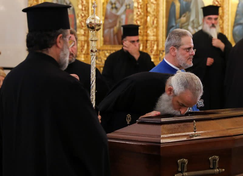 A Greek Orthodox priest pays his respects next to the coffin of the late Archbishop Chrysostomos II in the Apostle Varnavas Cathedral in Nicosia