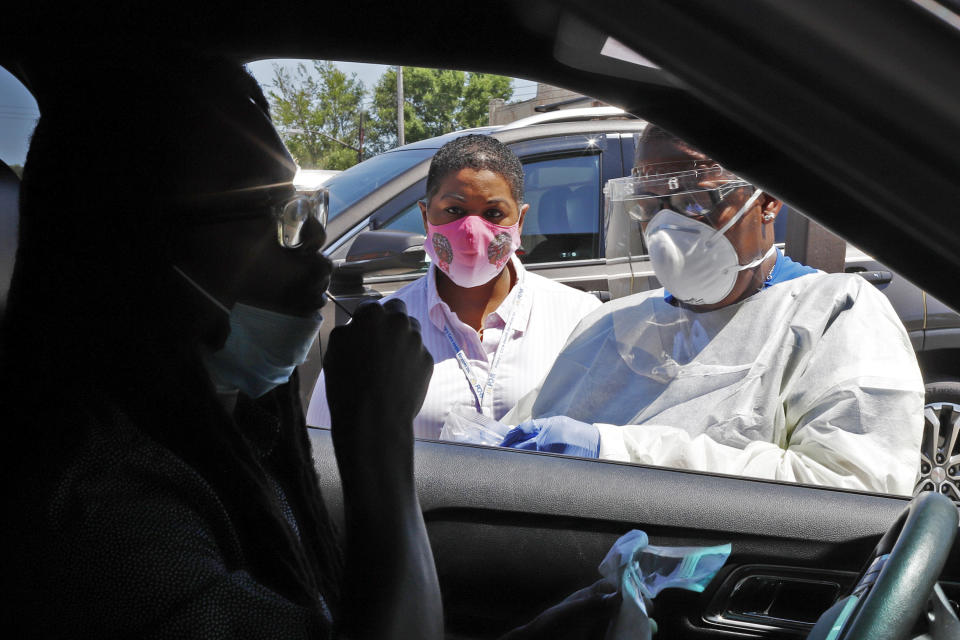 In this photo made on Monday, July 20, 2020, Kiva A. Fisher-Green, center, watches as nurse Ruth John, right, takes a sample from Walter Lewis for a COVID-19 test in the driveway of the Alma Illery Medical Center in the Homewood neighborhood of Pittsburgh. In March and April when Philadelphia and its surroundings became one of the nation's hot-spots for COVID-19 cases, Pittsburgh seemed at the time, to be under more control: the city racked up a fraction of the coronavirus cases as the other side of Pennsylvania. (AP Photo/Gene J. Puskar)