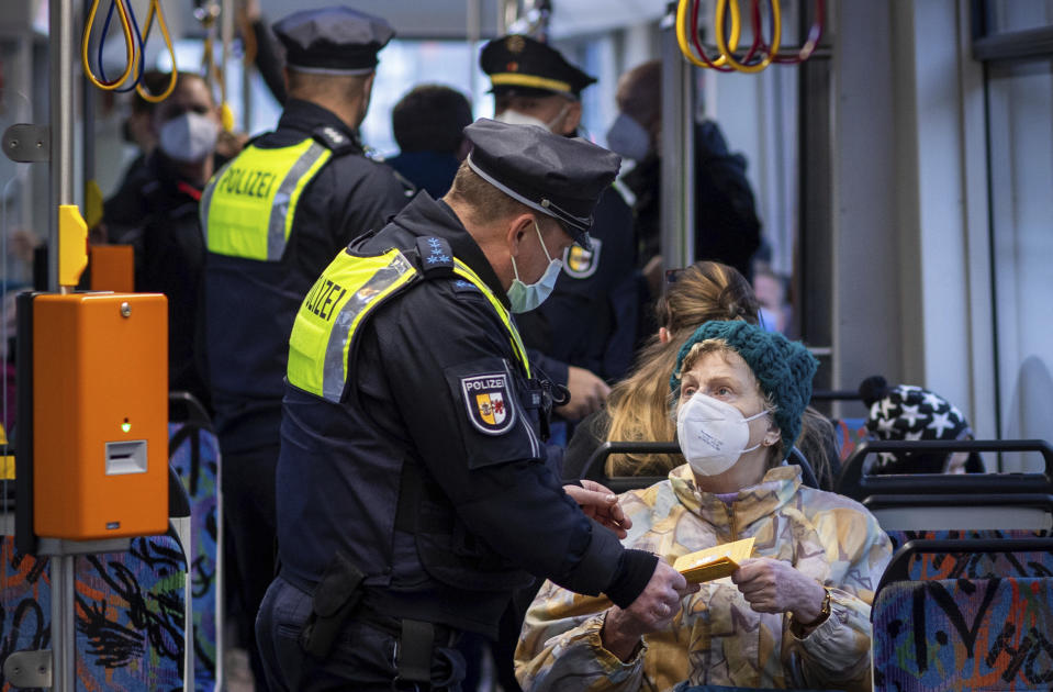 A police officer checks a vaccination card of a passenger in a tram in Schwerin, Germany, Tuesday, Dec. 14, 2021. In Mecklenburg-Western Pomerania, police and public order offices check compliance with 3G rules during a day of action as part of the Corona protection measures in local public transport. (Jens Buettner/dpa via AP)