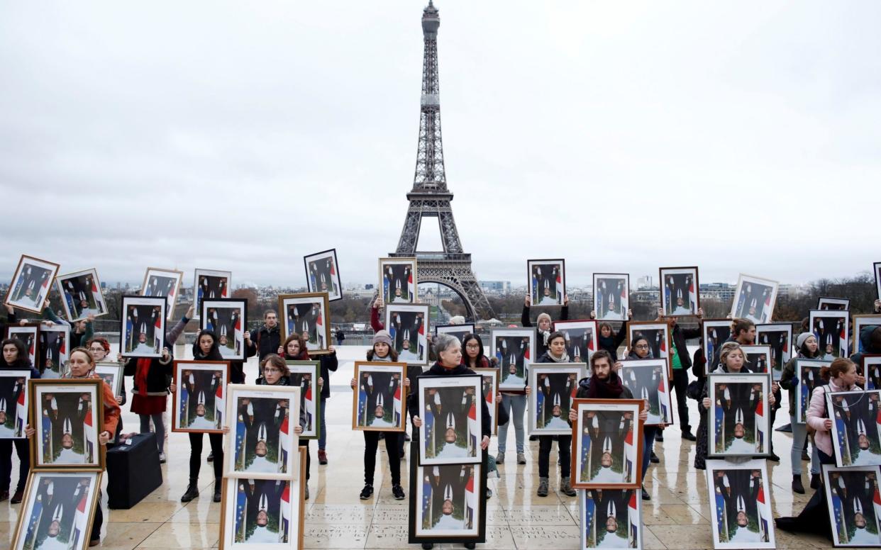 French climate activists hold inverted portraits of French President Emmanuel Macron during a Climate Change protest in front of the Eiffel Tower - REUTERS