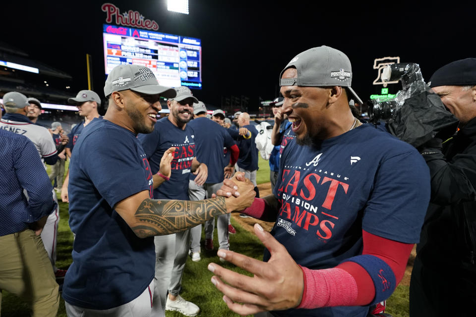 Atlanta Braves' Eddie Rosario, left, and Orlando Arcia celebrate after clinching their sixth consecutive NL East title by defeating the Philadelphia Phillies in a baseball game, Wednesday, Sept. 13, 2023, in Philadelphia. (AP Photo/Matt Slocum)