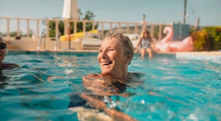 Senior woman enjoying a swim in a pool on a sunny day.