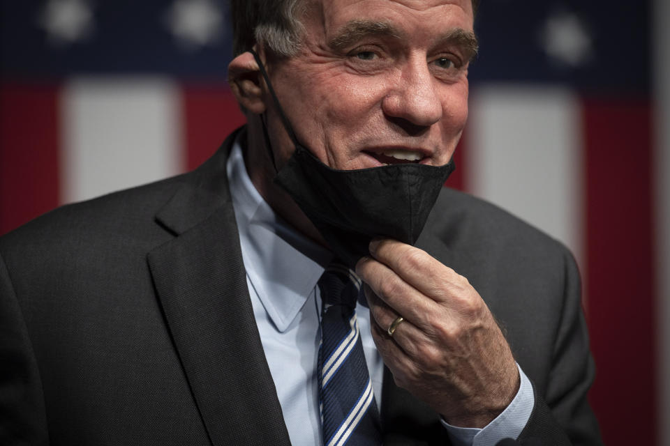 Sen. Mark Warner, D-Va., adjusts his mask after addressing the news media about his Senate race against Daniel Gabe, on election night in Alexandria, Va., Tuesday, Nov. 3, 2020. (AP Photo/Cliff Owen)