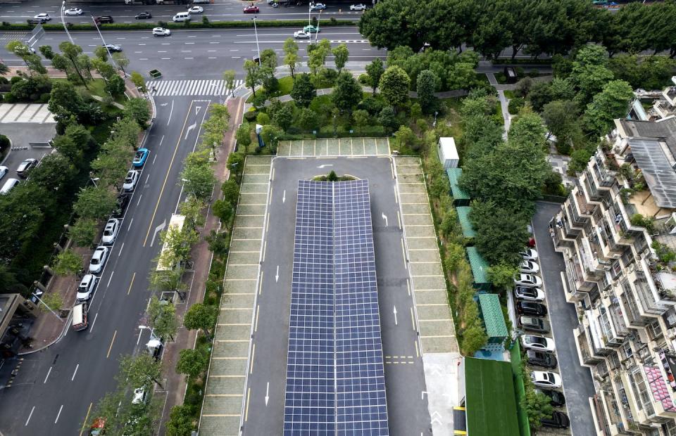 Apartments in a tower in China look down on an EV charging station covered in solar panels. <a href="https://www.gettyimages.com/detail/photo/looking-down-on-a-community-parking-lot-with-solar-royalty-free-image/1343714223" rel="nofollow noopener" target="_blank" data-ylk="slk:Zhihao/Moment via Getty Images;elm:context_link;itc:0;sec:content-canvas" class="link ">Zhihao/Moment via Getty Images</a>